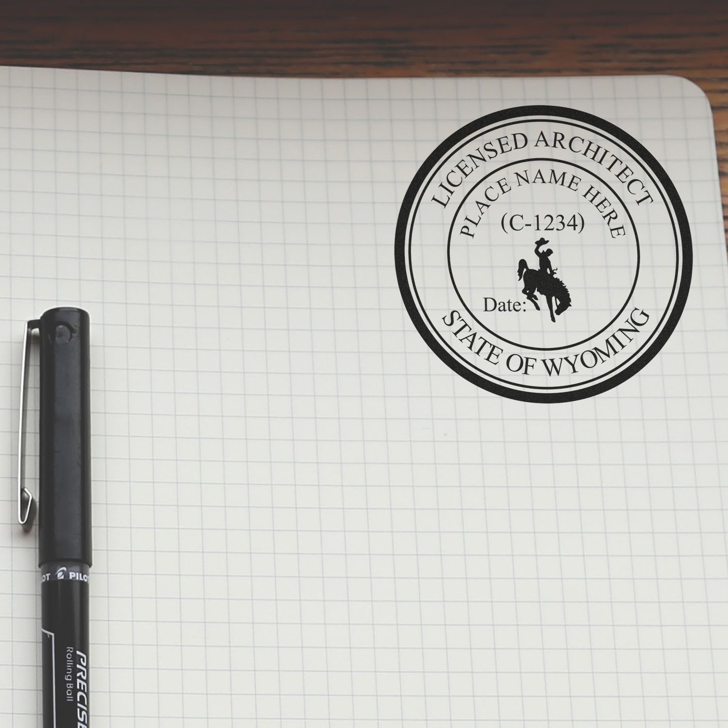 Premium MaxLight Pre-Inked Wyoming Architectural Stamp on graph paper with a pen beside it, displaying a Wyoming architect seal.