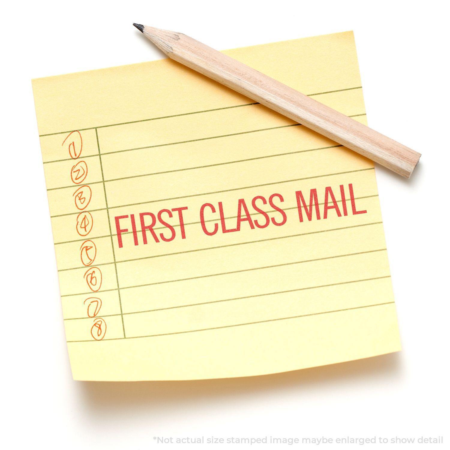 Jumbo Large Red First Class Mail Xstamper Stamp imprint on a yellow lined sticky note with a pencil placed diagonally on top.